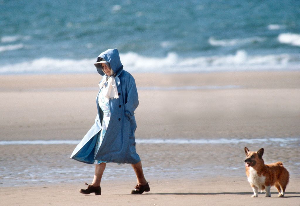 The Queen Mother walking with corgi on the beach in Norfolk