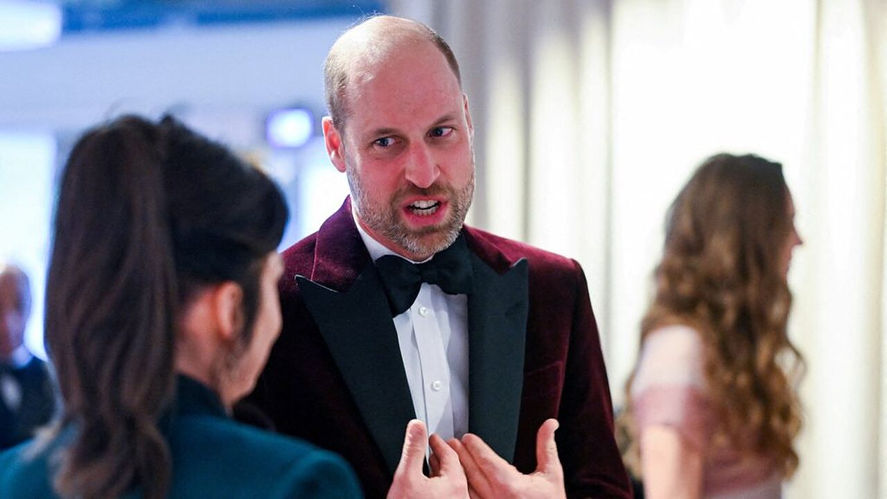 Britain's Prince William, Prince of Wales, meets with Jane Millichip, CEO of the British Academy of Film and Television Arts. He is pictured speaking to her while wearing a maroon velvet suit.